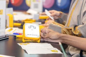 Participant holding a JuniorBuddy solar light they assembled during a SolarBuddy LIVE Hour of Power team-building event.